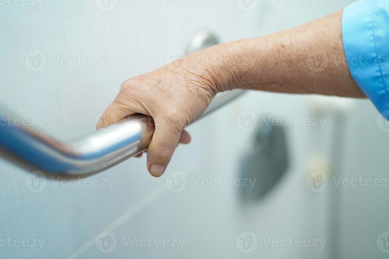 Aziatische senior vrouw patiënt gebruik toilet badkamer handvat beveiliging foto