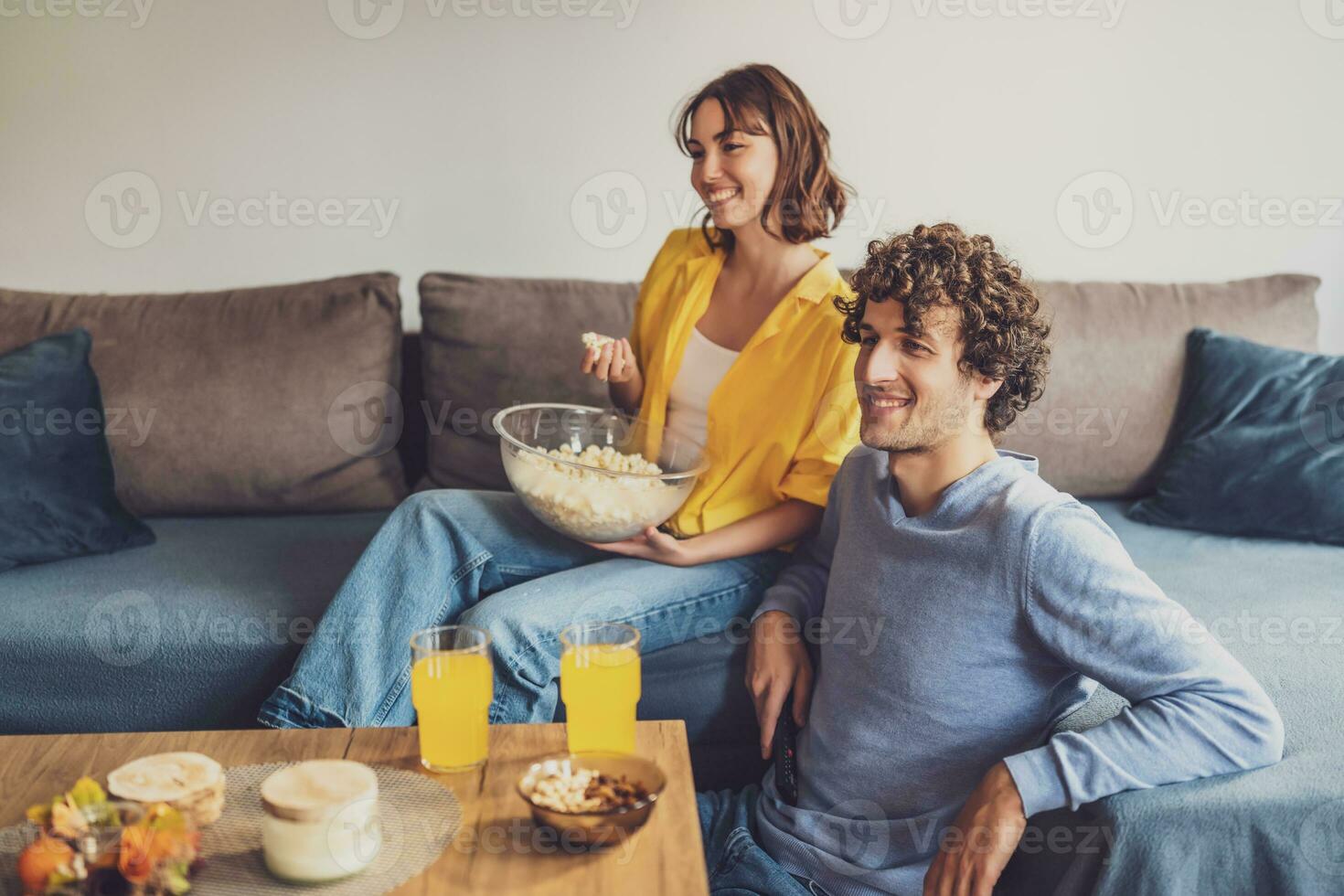 portret van jong gelukkig paar wie is ontspannende en aan het kijken TV Bij huis. foto