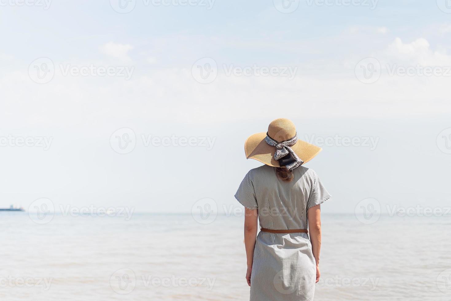 vrouw in zomerkleren staande op een pier, zee op de achtergrond foto