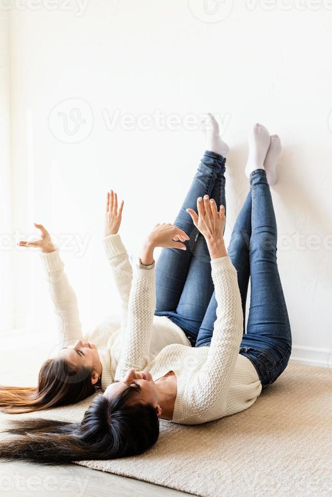 twee vrouwen die op het tapijt liggen, benen omhoog en plezier hebben foto