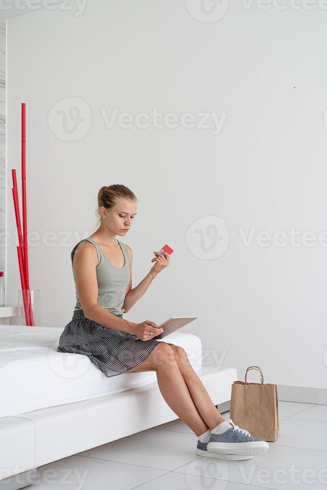 jonge vrouw die online winkelt om thuis op bed te zitten foto