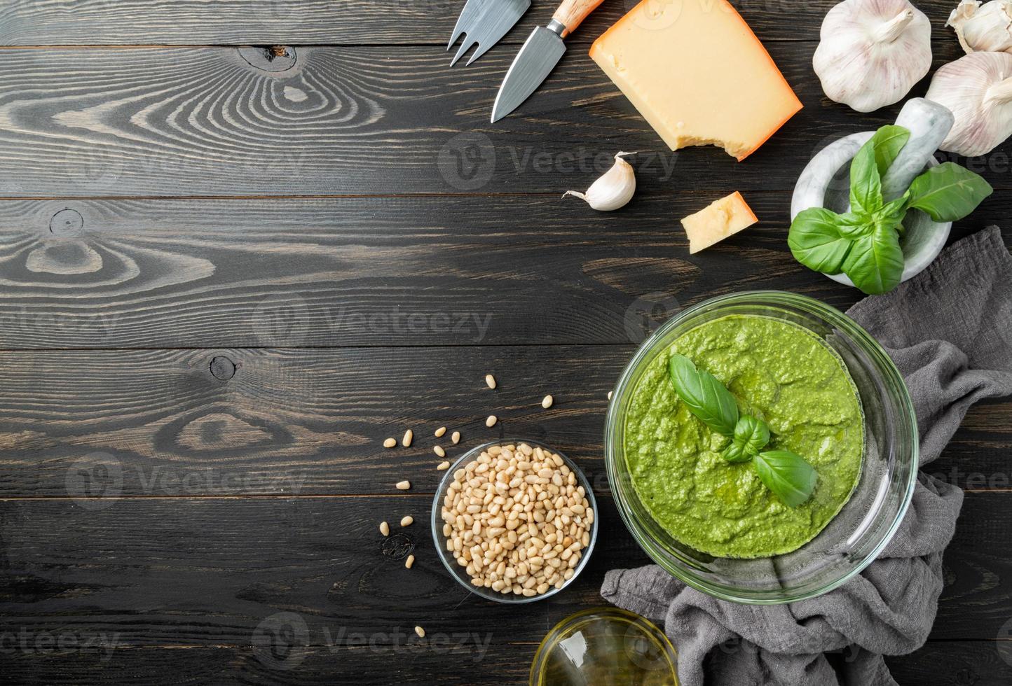 verse pesto in kom met ingrediënten, bovenaanzicht plat op zwart foto