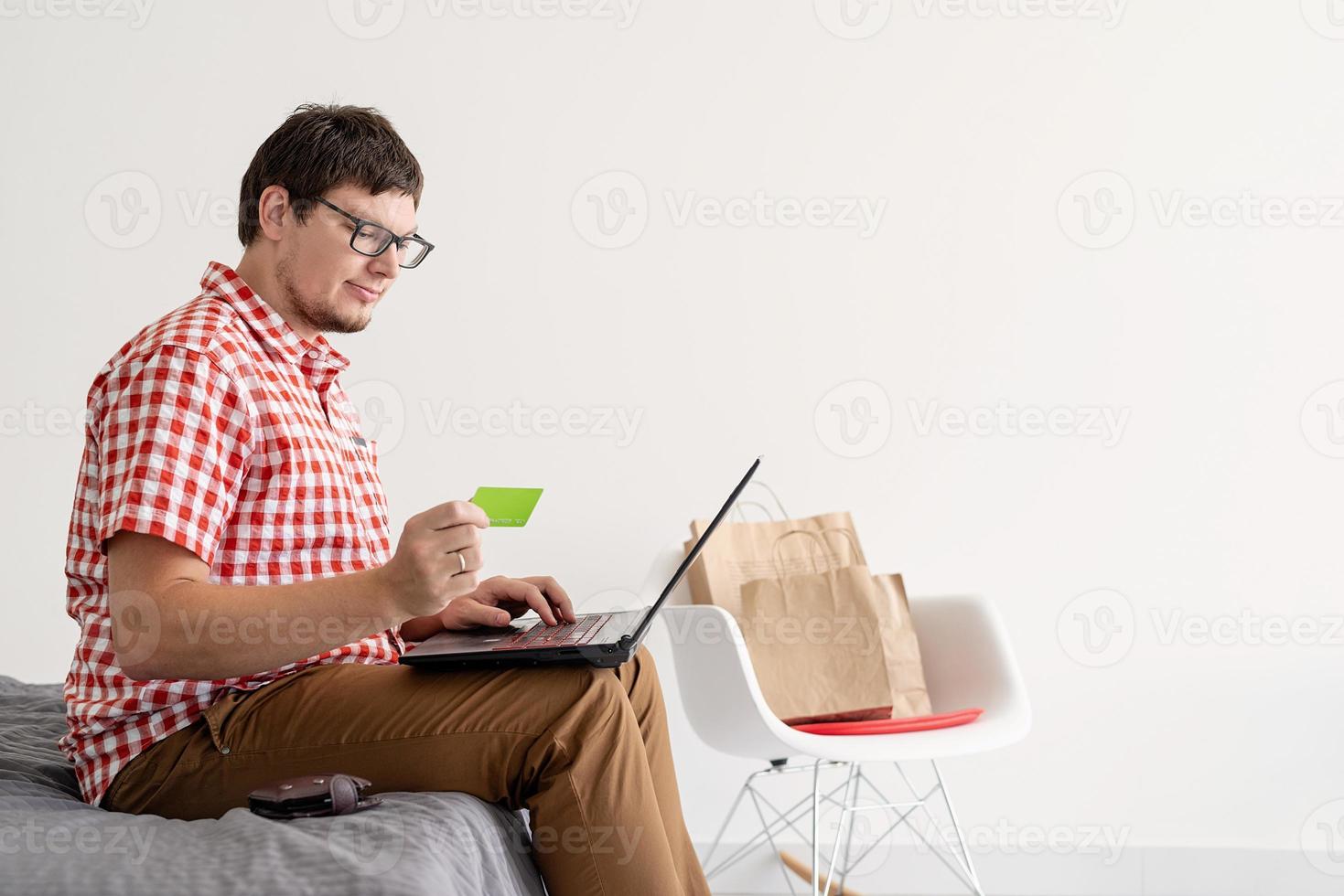 jonge man winkelen op internet met laptop foto