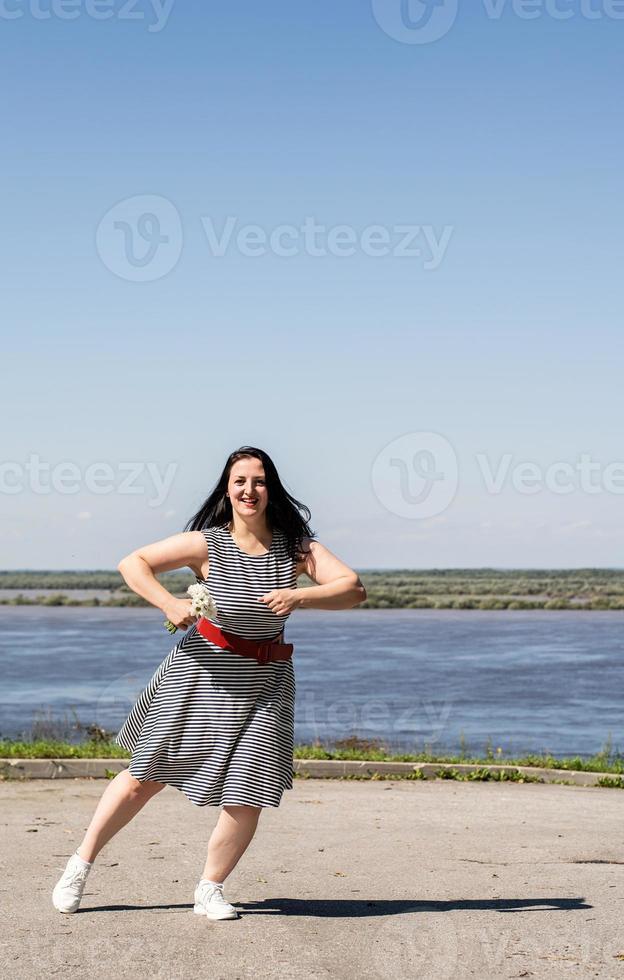 jonge vrouw met bloemen en dansen op de achtergrond van de rivier foto