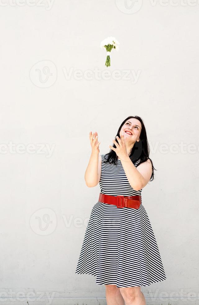 gelukkige jonge vrouw die een boeket bloemen in de lucht gooit foto