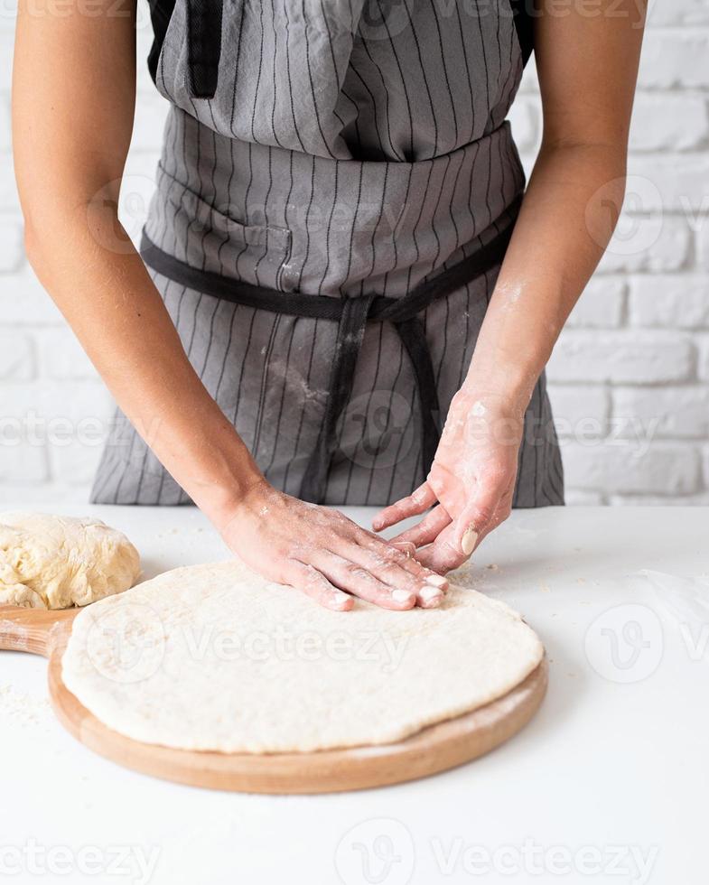 vrouw die deeg kneedt thuis pizza voorbereiden foto