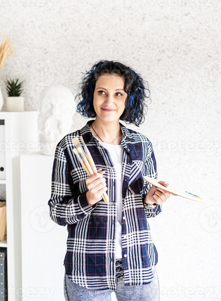 lachende vrouw kunstenaar in haar atelier met kunstpalet en verf foto