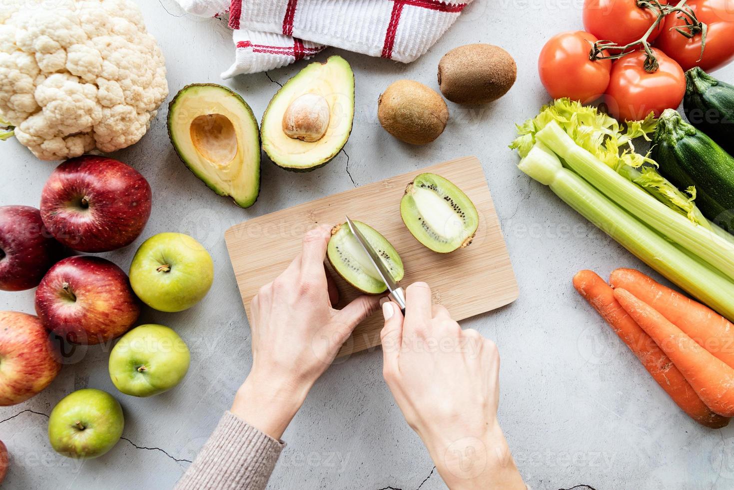 vrouwelijke hand die een kiwi snijdt voor detox-dieet bovenaanzicht plat leggen foto