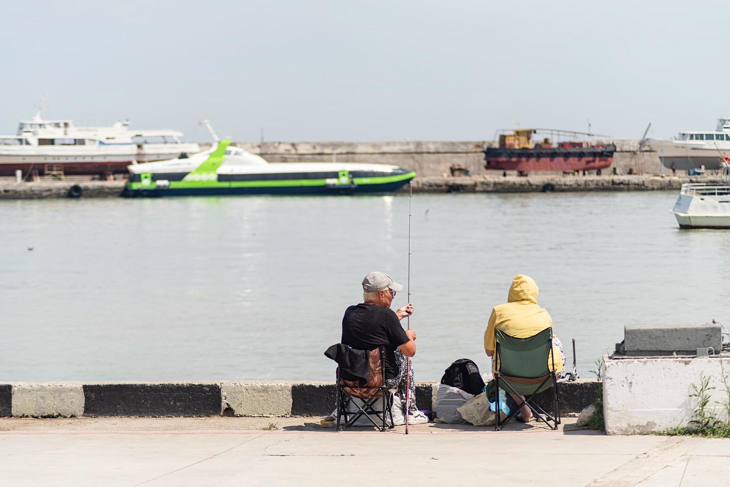 yalta 2021- mensen vissen op de dijk, boten en jachten op de achtergrond foto