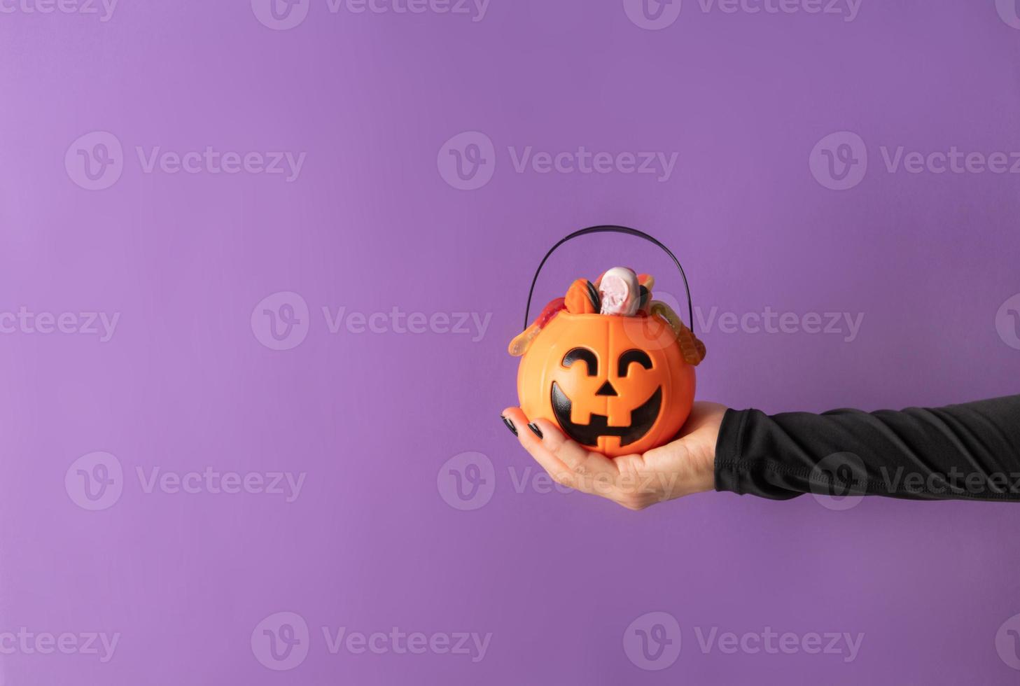 vrouw halloween hand met zwarte nagels met pompoen vol snoep foto