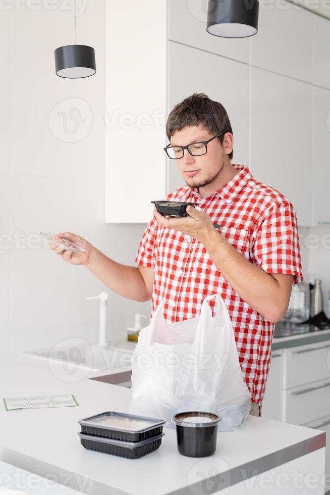 man met een wegwerp plastic zak met voedselbezorging in de keuken foto