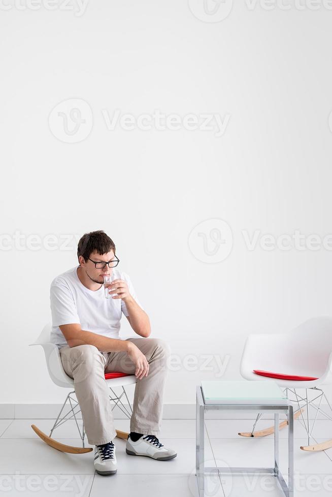 jonge depressieve man met hoofdpijn zittend op de stoel foto