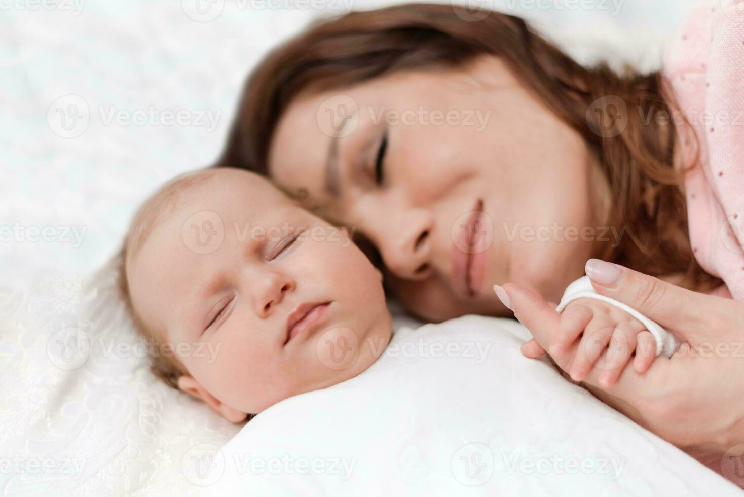 jong mooi vrouw Holding klein hand- van haar slapen baby dochter in slaapkamer foto