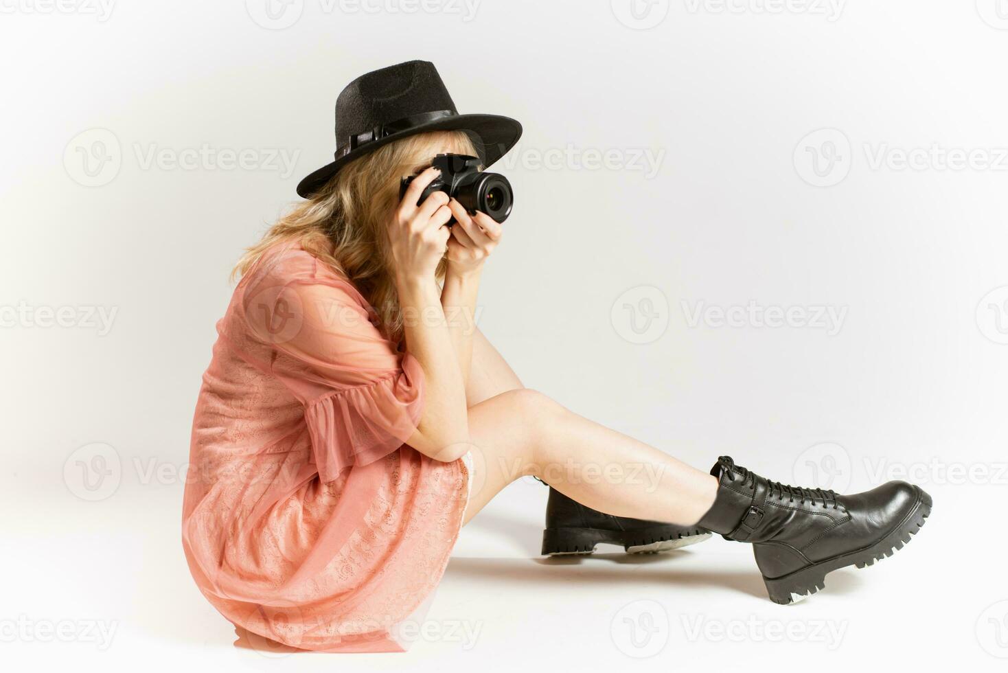 portret van een schattig meisje fotograaf in een hoed poseren met een camera in haar handen in de studio Aan een wit achtergrond foto