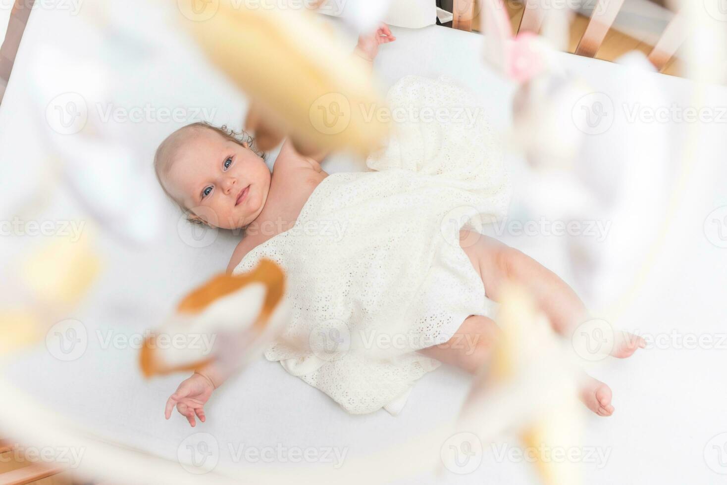 portret van een mooi baby meisje leugens Aan een wit vel in haar kamer foto