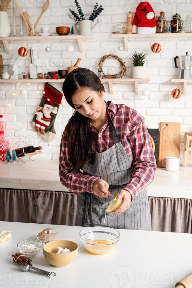 Latijnse vrouw die de honing bij het deeg giet dat bij de keuken kookt foto