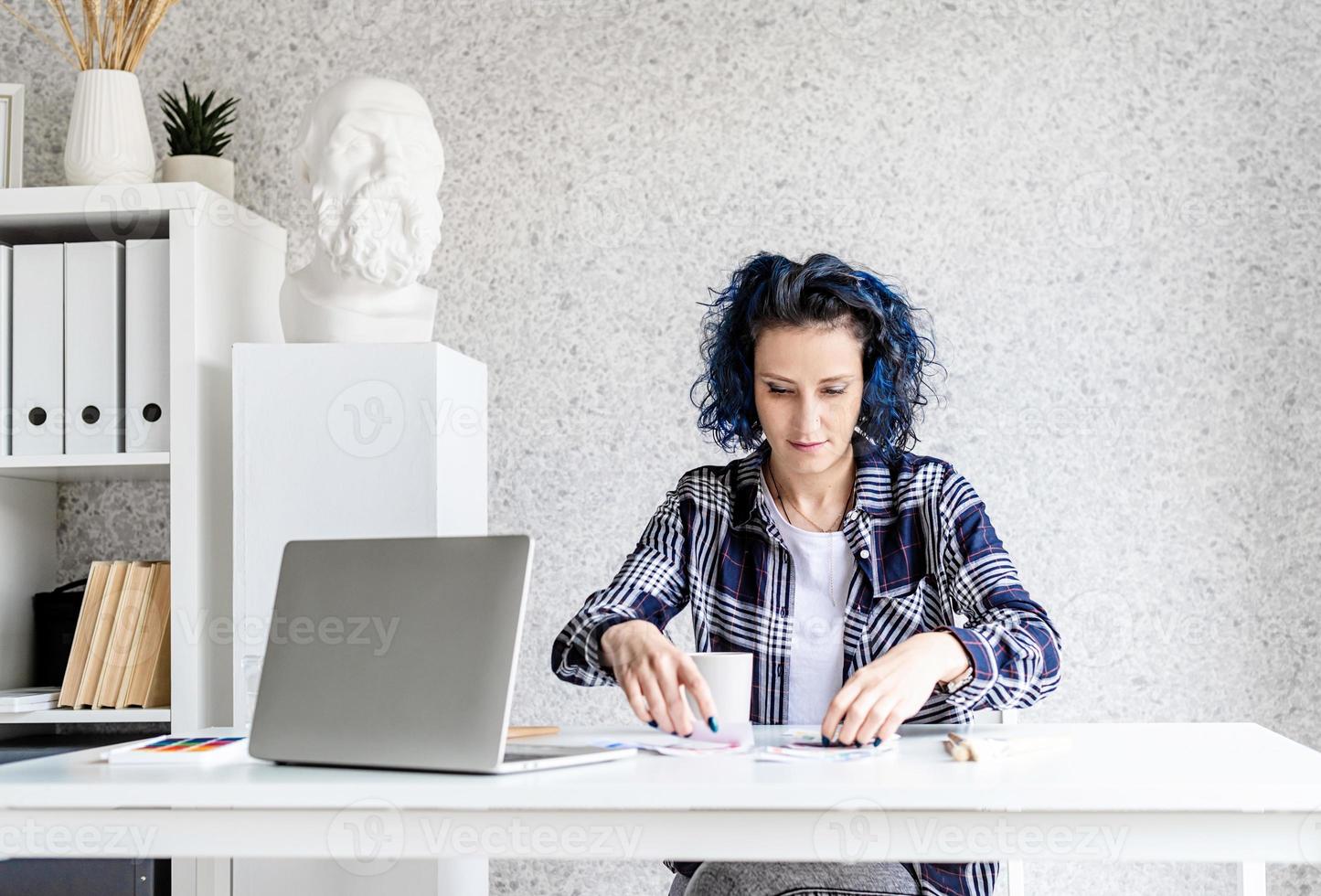 ontwerper aan het werk met kleurenpaletten en laptop in haar studio foto