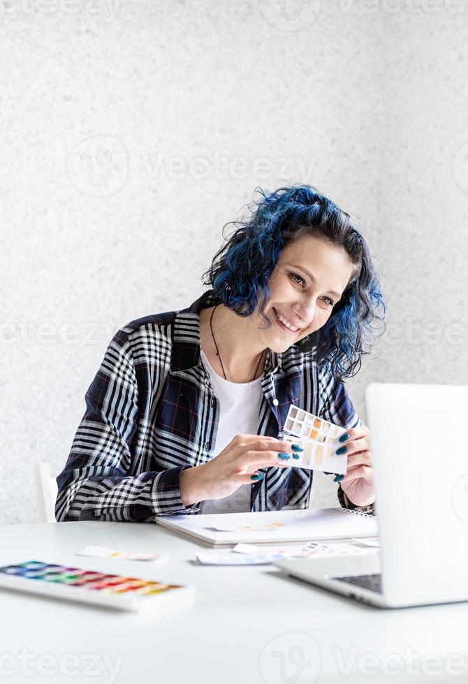 ontwerper aan het werk met kleurenpaletten en laptop in haar studio foto