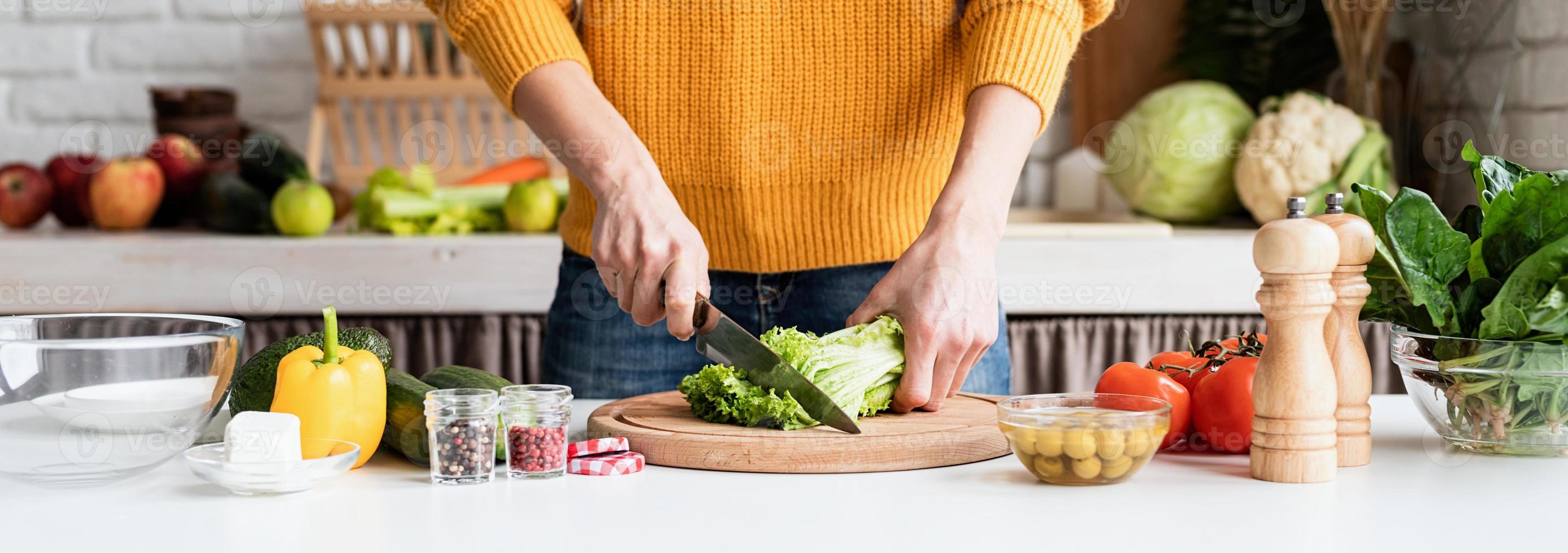 vrouw bereidt Griekse salade in de keuken die sla snijdt foto