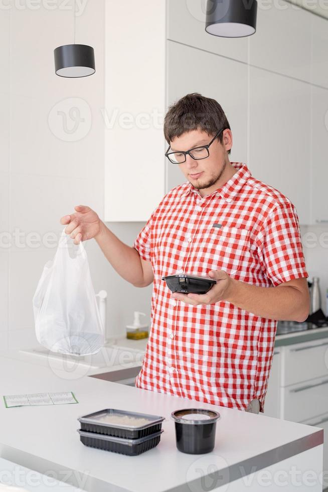 man met een wegwerp plastic zak met voedselbezorging in de keuken foto