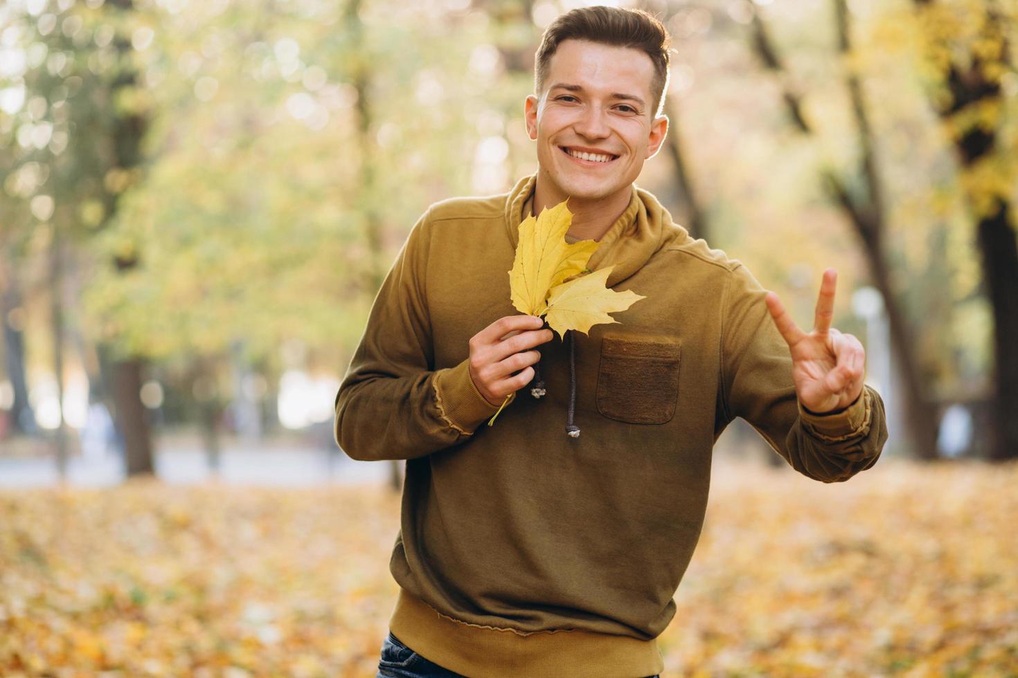 man die lacht en een boeket herfstbladeren vasthoudt in het park foto