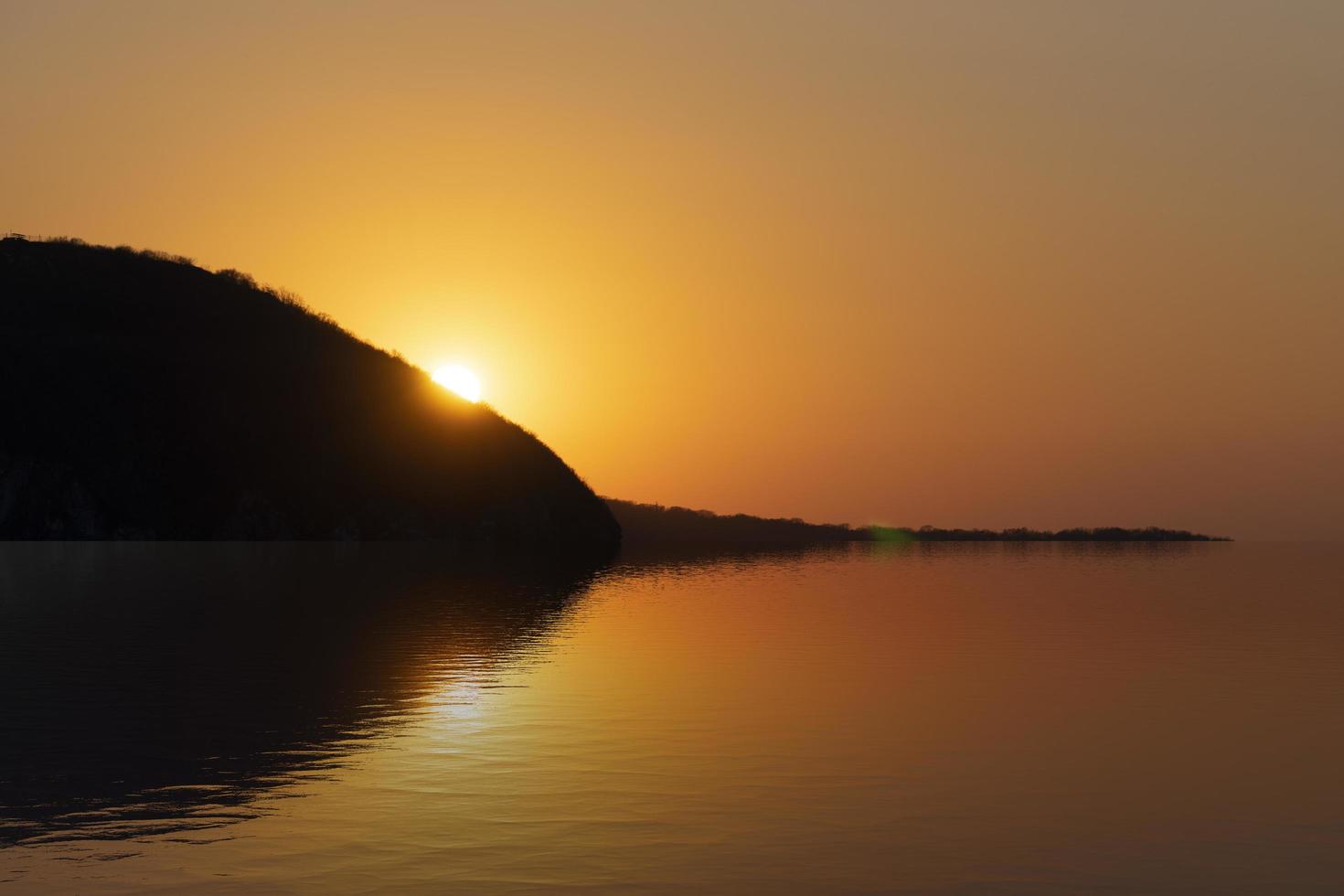 zeegezicht met oranje zonsondergang en zon foto