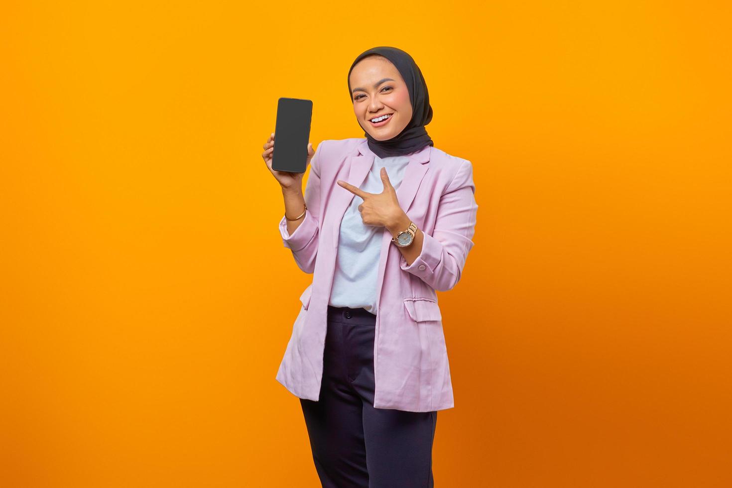 jonge aziatische vrouw die vrolijk met haar vinger op smartphone wijst foto