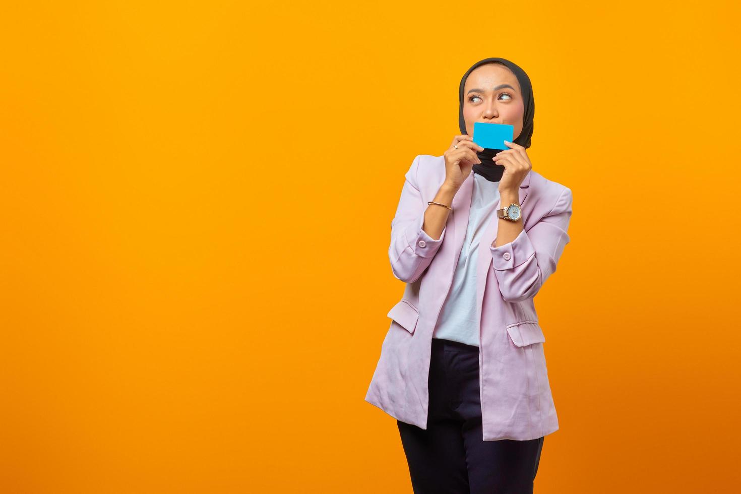 mooie jonge aziatische vrouw die mond bedekt met creditcard foto