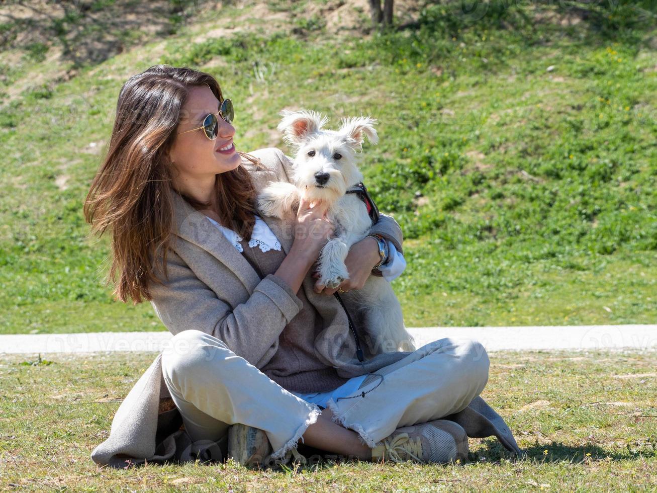 jonge vrouw die tijd doorbrengt met haar witte schnauzerpuppy. foto