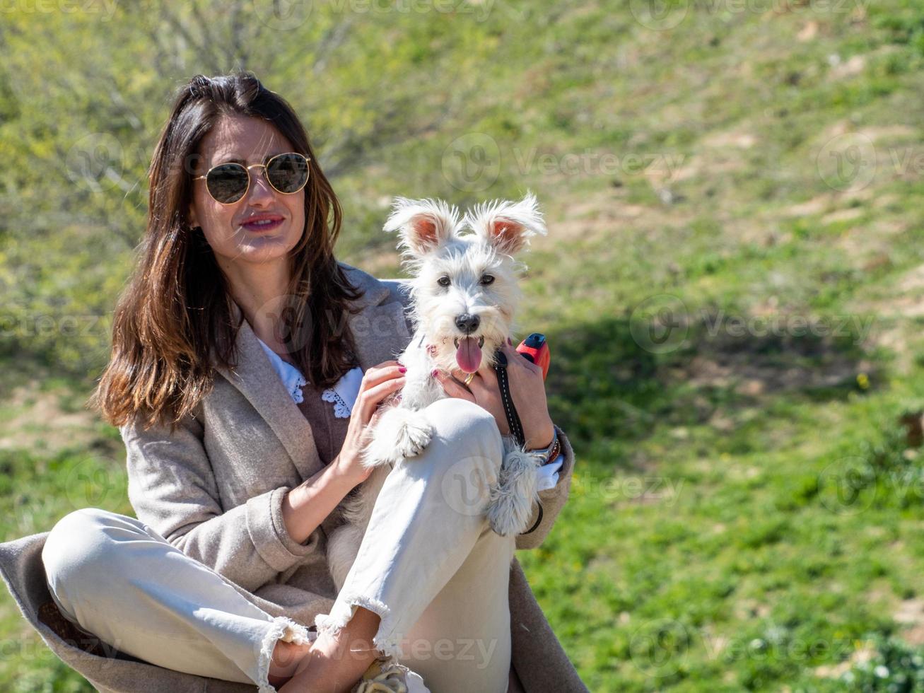 jonge vrouw poseren voor een foto met haar witte schnauzer puppy.