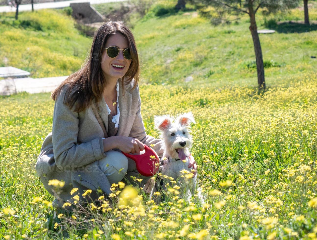 gehurkte jonge vrouw kijkt naar de camera met haar schnauzerhond foto