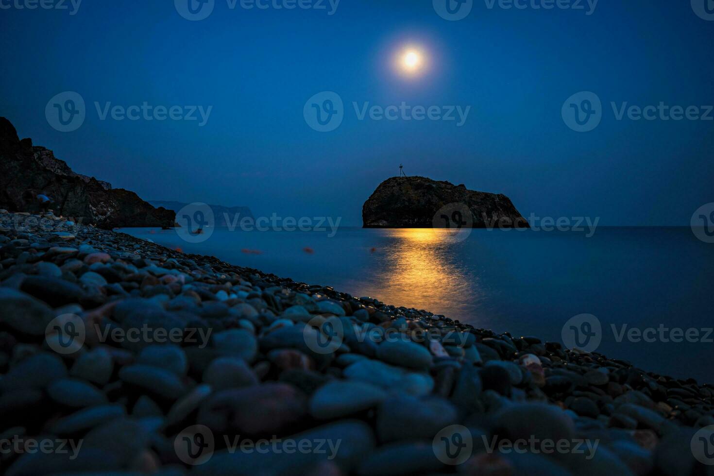 sterrenhemel nacht met een vol maan over- zee met rots in voorkant. kaap gewelddadig, Jasper strand rots van de heilig fenomeen met een kruis Aan de achtergrond van de maan foto