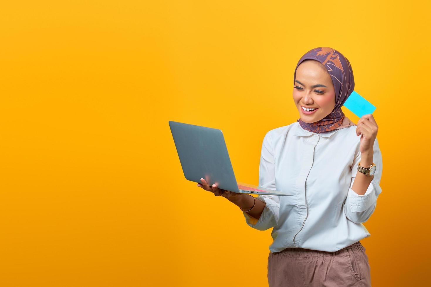 vrolijke aziatische vrouw die laptop vasthoudt en blanco kaart toont foto