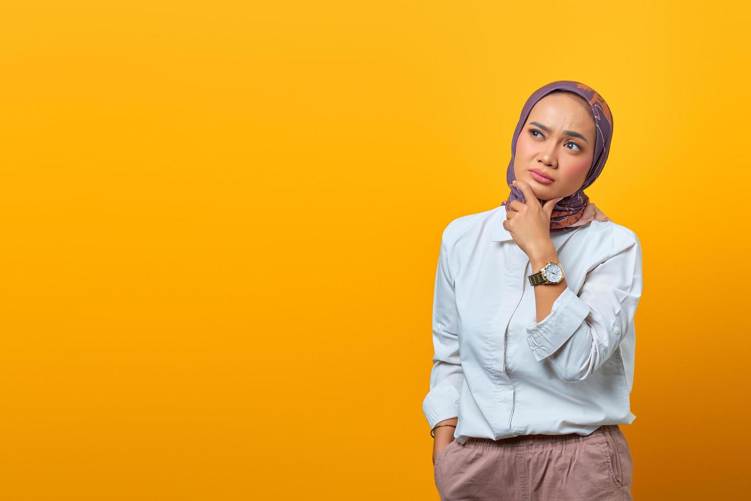 denkende aziatische vrouw die kin aanraakt en naar lege ruimte kijkt foto