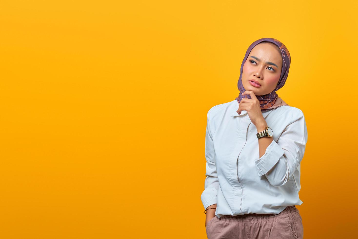 denkende aziatische vrouw die kin aanraakt en naar lege ruimte kijkt foto