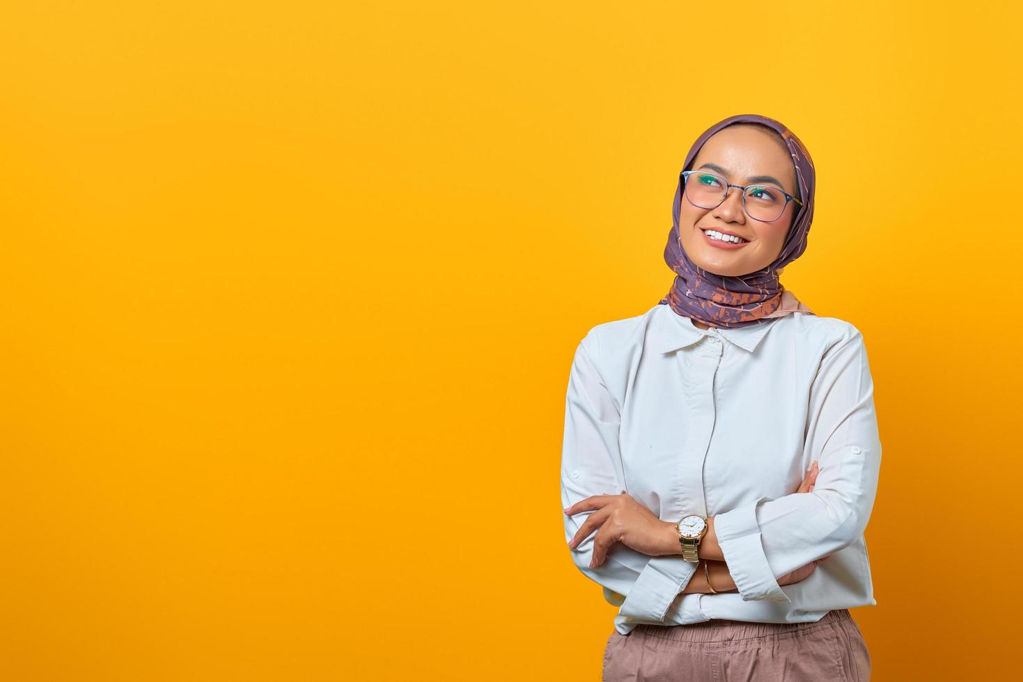 portret van vrolijke aziatische vrouw met gekruiste armen en omhoog kijkend foto