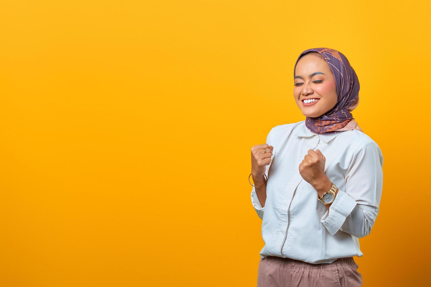 opgewonden aziatische vrouw sloot ogen en viert overwinning glimlachend foto