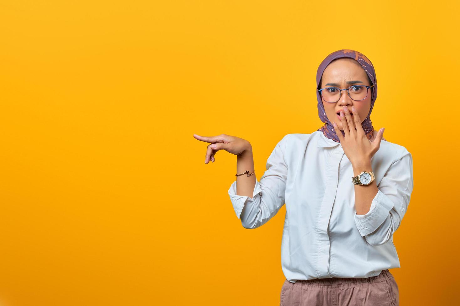 geschokte aziatische vrouw die met vinger naar lege ruimte wijst foto