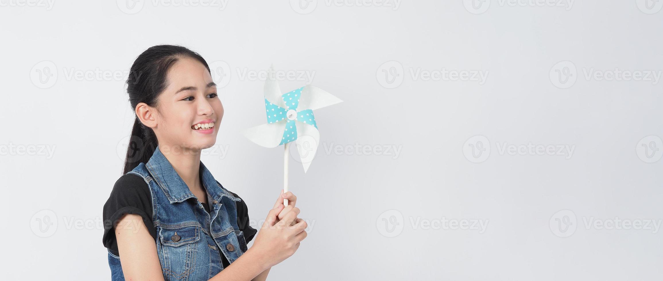 tiener vrouw en papier windmolen speelgoed. tiener met windwielstok foto