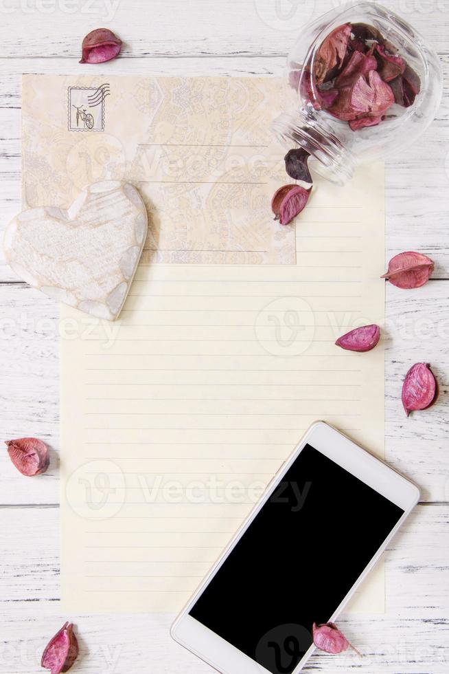 papier met bloemblaadjes, telefoon en hart foto