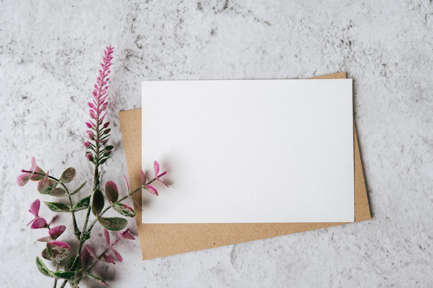 een blanco kaart met envelop en bloem wordt op een witte achtergrond geplaatst foto