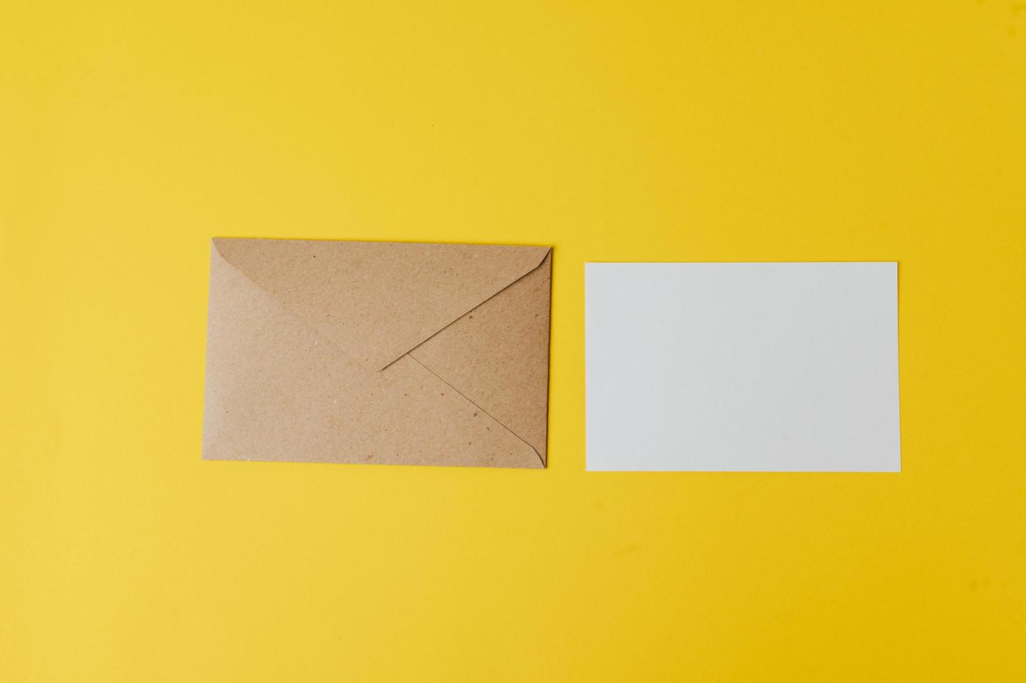 een blanco kaart met envelop wordt op een gele achtergrond geplaatst foto