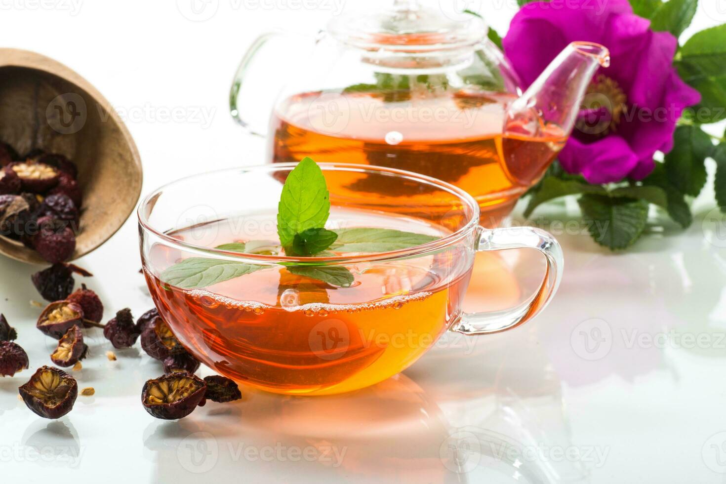 gebrouwen rozenbottel thee in een glas theepot met rozenbottel bloemen en munt foto