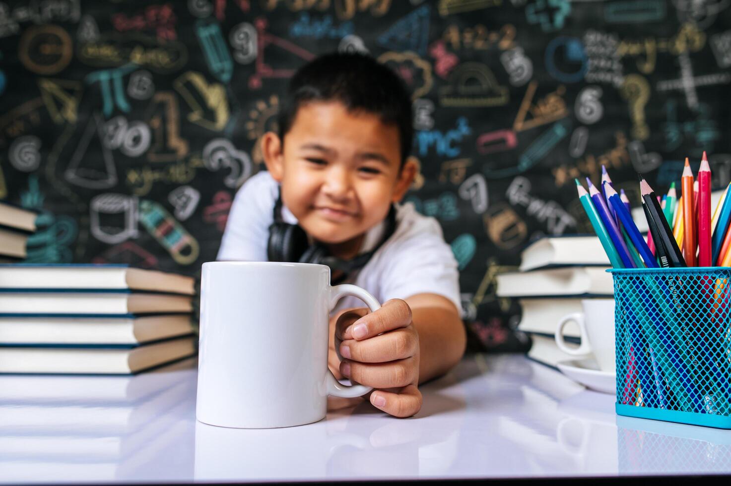 kind zit en houdt een beker vast in de klas foto