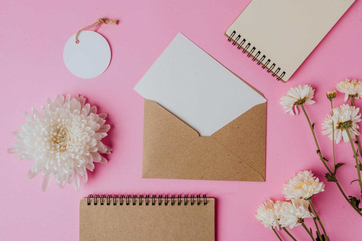 bruine envelop, tag, notitieboekje met blanco kaart en bloem foto
