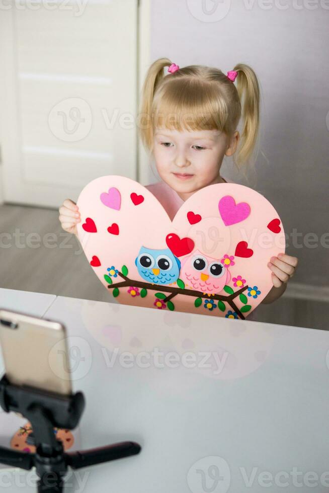 een blogger meisje maakt een voelde ambacht voor Valentijnsdag dag in de vorm van een hart. de concept van kinderen creativiteit en handgemaakt. foto