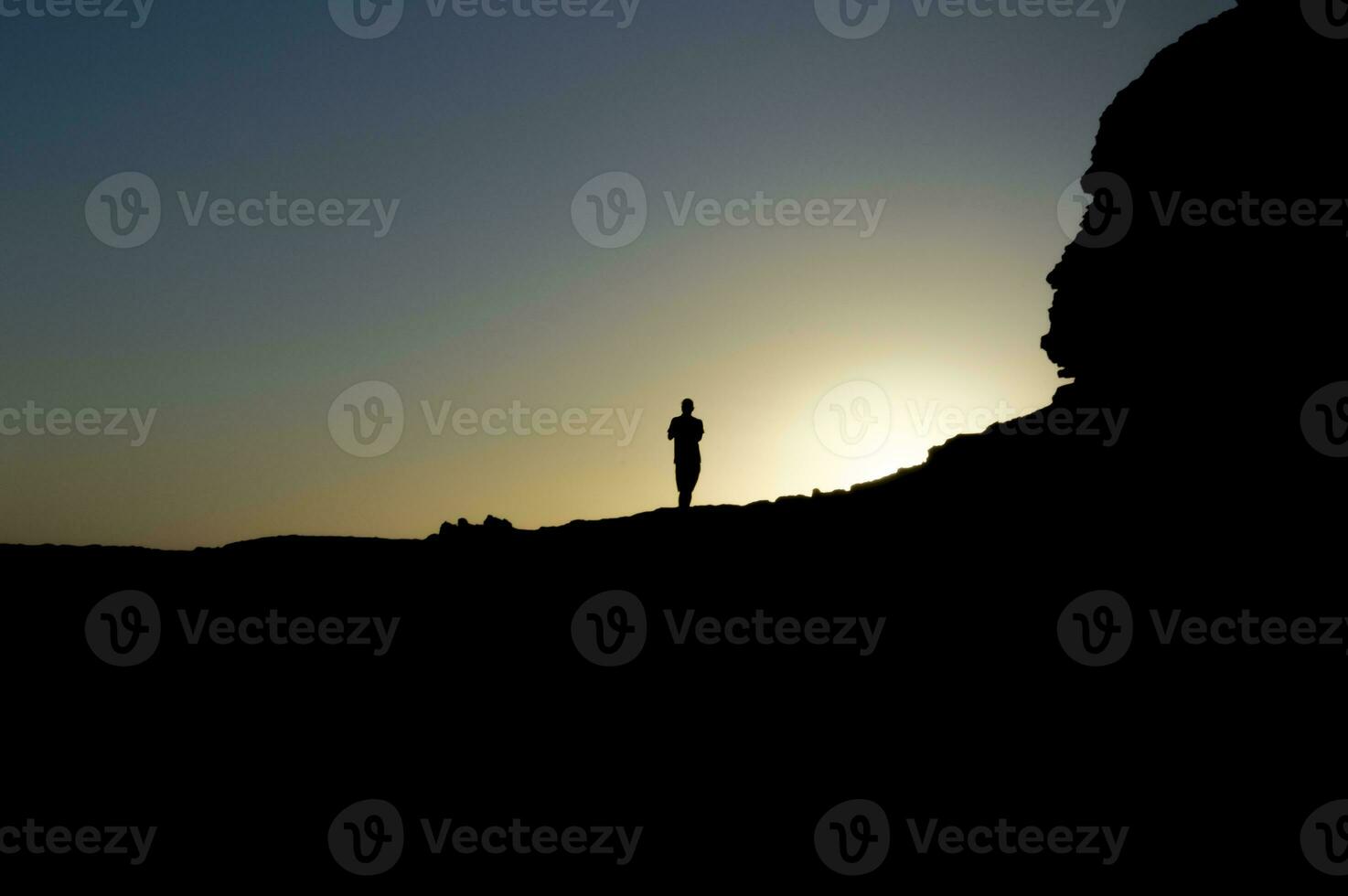 beeld van de silhouet van een Mens Aan een rots met de zon verlicht, silhouet van een persoon Aan een steen, ondernemerschap concept foto