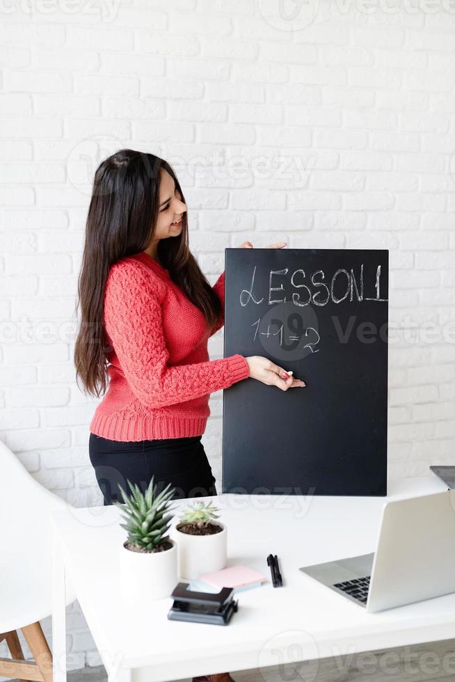 jonge latijnse vrouw met zwarte koptelefoon die online engels leert foto