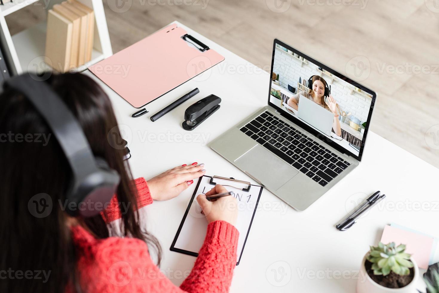 jonge latijnse vrouw met zwarte koptelefoon die online engels leert foto