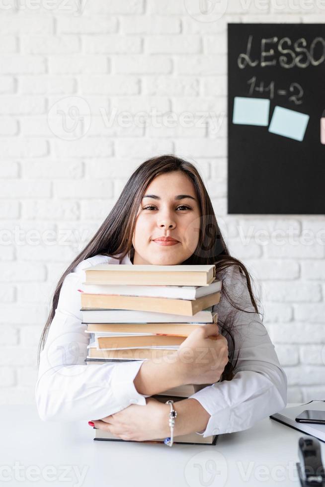 jonge leraar zit met stapel boeken wegkijkend klaar voor les foto